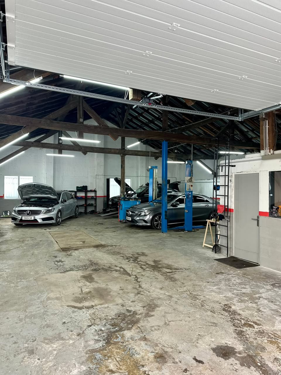Atelier de Fensch Car Service à Nilvange : deux ponts élévateurs bleus et une Mercedes Classe A blanche sous verrière